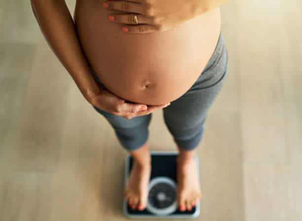 Femme enceinte qui se pèse sur une balance